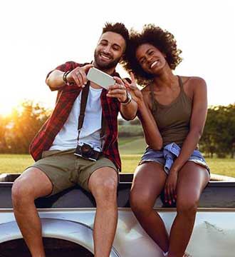 Couple sitting on truck taking selfie