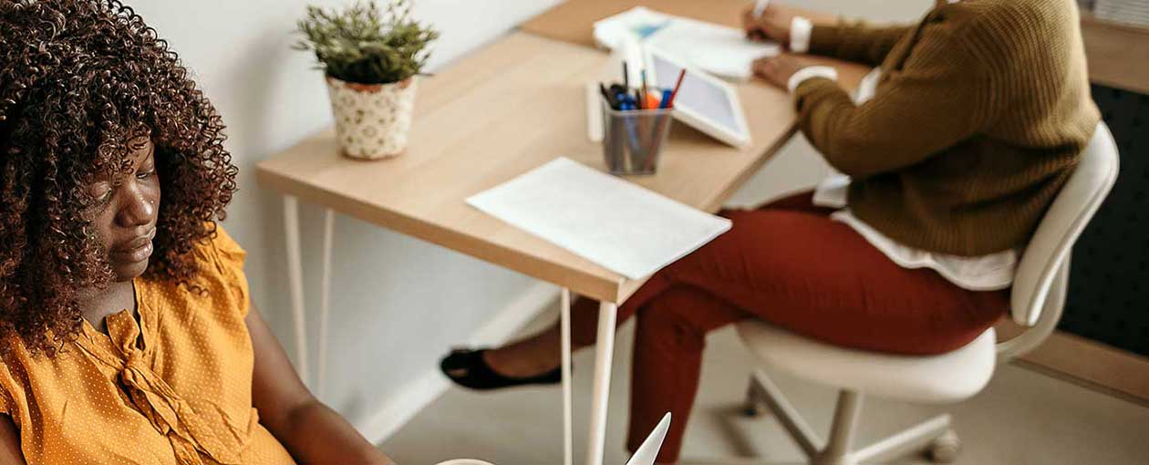 Two ladies sitting at desk and chair.